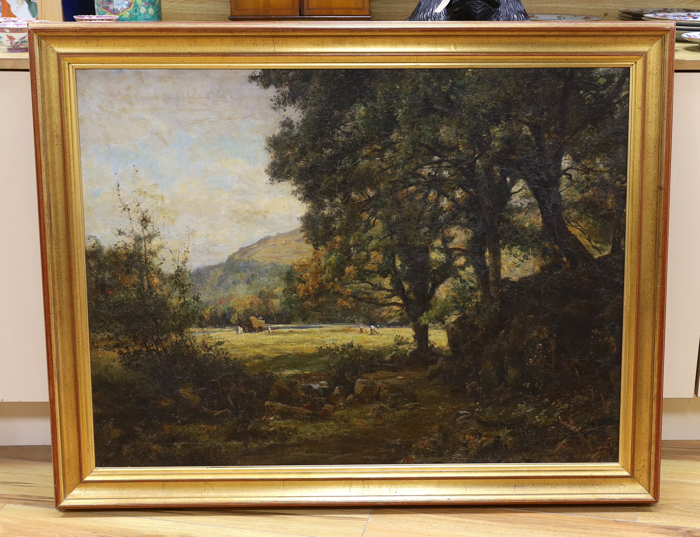 Oil on canvas, Woodland before a clearing with figures hay making, indistinctly signed, possibly K G So...?, 73 x 98cm